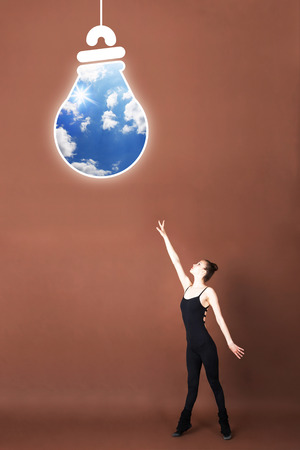 Girl reaches for light bulb idea businessの写真素材