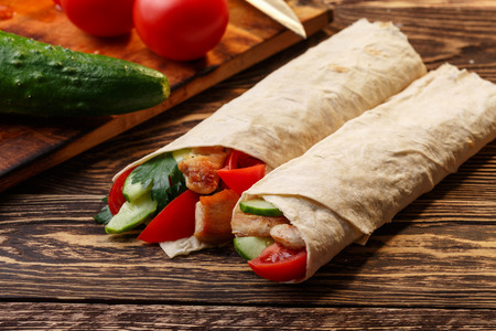 Traditional shawarma wrap with chicken and vegetables near its ingredientsの写真素材
