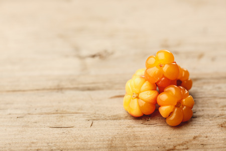 Cloudberries (moroshka) on a wooden table. Wild northern berry. Shallow depth of fieldの写真素材