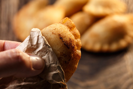 Male hand holding fried colombian empanada. Savory stuffed patties also known as pastel,pate or...