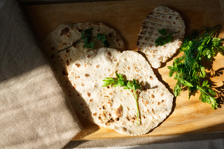 Indian naan bread on wooden table next to greensの写真素材