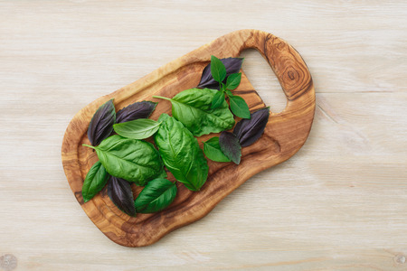 Heirloom basil on olive wood cutboard. The cultivars including Genovese, Holy Basil, spice globe. Flat lay, above viewの写真素材