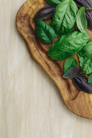 Heirloom basil on olive wood cutboard. The cultivars including Genovese, Holy Basil, spice globe. Flat lay, above viewの写真素材