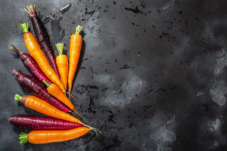 Carrots, orange and purple anthocyanin-rich on washed concrete backdrop with copy space, top view