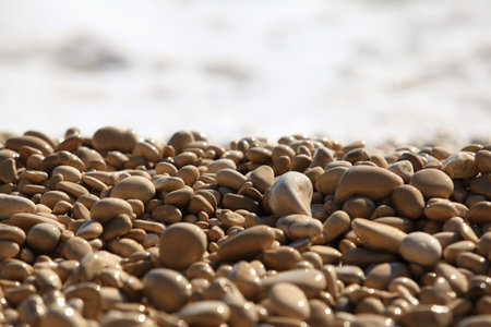Wet pebble against a sea surf. Close up.