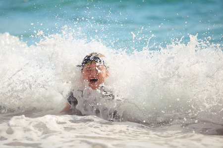 The boy swiming in sea waves on a beachの写真素材