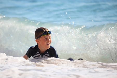 The boy swiming in sea waves on a beachの写真素材