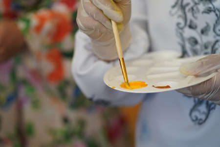 Hand in a rubber glove painting a picture with paints on canvasの写真素材