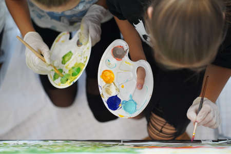 Palette with paints in the hands of artists. With rubber gloves and without but ready for work.の写真素材