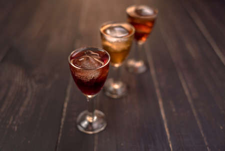 Alcoholic drinks in glass piles on a wooden table. Cherry, nut and lemon liqueurs.の写真素材