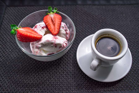 Strawberry ice cream with a cup of coffee on a black backgroundの写真素材