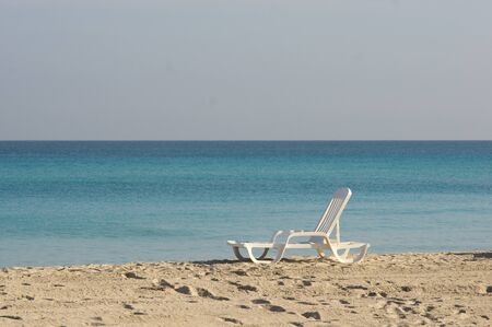 Alone empty sunbed on a sand beach by the oceanの写真素材