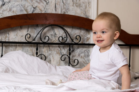 the baby is sitting on the bed and smiling cuteの写真素材