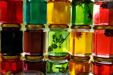 Multicolored honey in a jar on the counter. Colored jars with sweet honey or jamの写真素材