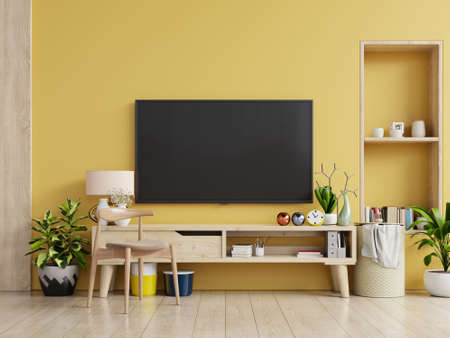 TV on cabinet in modern living room with lamp,table,flower and plant on yellow wall background,3d renderingの写真素材