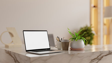 Minimalist home office interior featuring a laptop with blank screen on marble desk, coffee cup, stationery, and potted plant- 3D renderingの写真素材