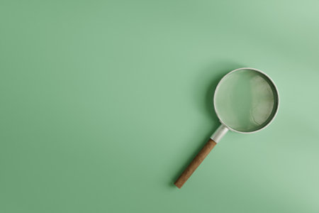 A magnifying glass with a wooden handle placed on a clean mint green background- 3D renderingの写真素材