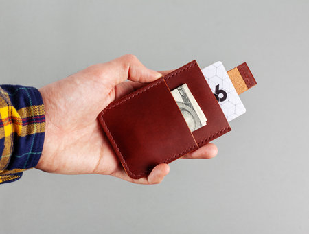 Leather cardholder with dollars and cards on a gray background.の写真素材