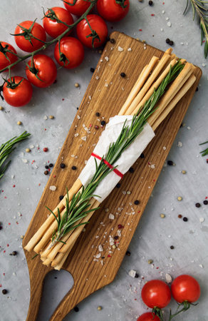 Italian grissini on a cutting board with vegetablesの写真素材