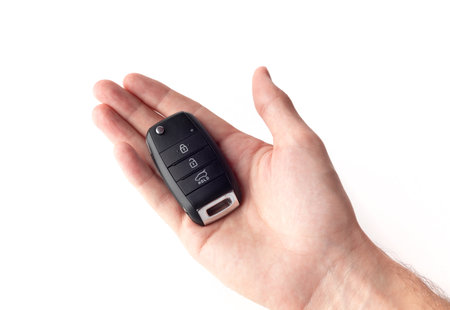 A man's hand holds the car key isolated on a white background close up.の写真素材