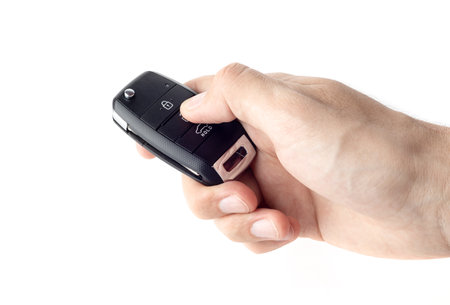 Unlocking a car with button on the keychain. Man's hand holds car key on white background close up.の写真素材