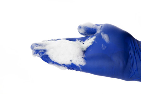 Hand in a blue latex glove isolated on white. A hand in a glove holds a foam for washing and cleaning.の写真素材