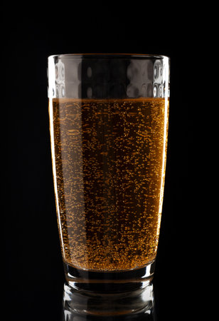 Glass with golden liquid in bubbles on a black background. Effervescent vitamin C pills with orange flavorの写真素材