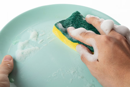 Men's hands washing dishes in sink with detergent. man doing homework washes large pile of dishes in kitchen sink, household chores, routine, duties.の写真素材