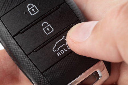 Open the trunk of a car with button on the keychain. man's hand holds car key on white background close up.の写真素材