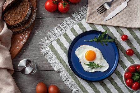 Fried eggs for breakfast. Healthy breakfast with vegetables and herbs. Fried egg on a blue plate. Serving on the table.の写真素材