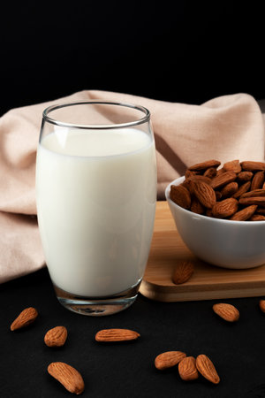 A glass of almond milk on the table, almonds scattered all around. Alternative milk from almonds lactose-free.の写真素材