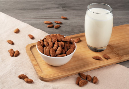 A glass of almond milk on the table, almonds scattered all around. Alternative milk from almonds lactose-free.の写真素材