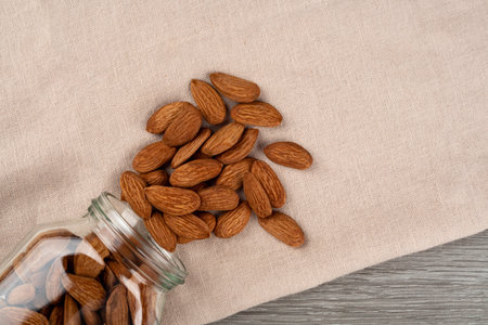 Scattered almonds from a glass jar on a white background.の写真素材