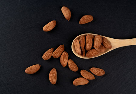 Spoon of almonds on a black background.の写真素材