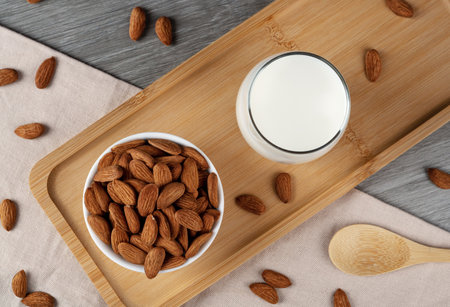 A glass of almond milk on the table, almonds scattered all around. Alternative milk from almonds lactose-free.の写真素材