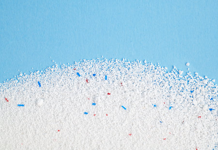 Washing powder with blue and red granules on a blue background close up, top view.の写真素材
