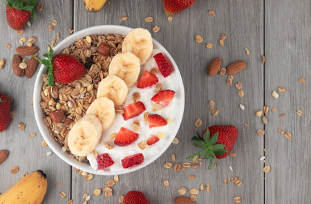 Yogurt with granola and fresh fruits on wooden table, top viewの写真素材