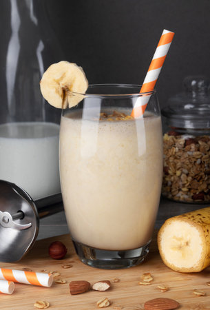 Banana smoothie in a glass with a straw on a wooden backgroundの写真素材