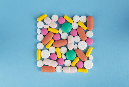 Colorful pills on blue background. Top view with copy space.