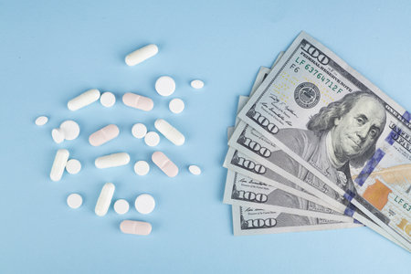 Pills and dollars on a blue background. The concept of expensive medicine.の写真素材