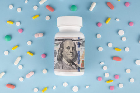 Top view of medical pills and dollar banknote on blue background.