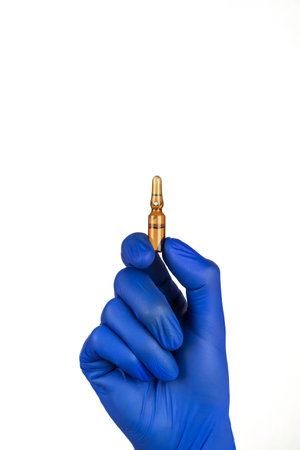Hand in blue glove holding ampoule isolated on white background.の写真素材