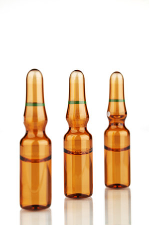 Three ampoules with reflection on a white background. Focus on the central ampoule.の写真素材