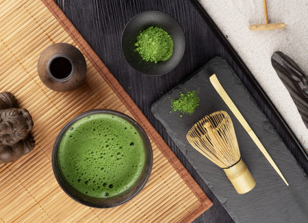 Matcha green tea in bowl, bamboo whisk, japanese bamboo mat and wooden chopsticks