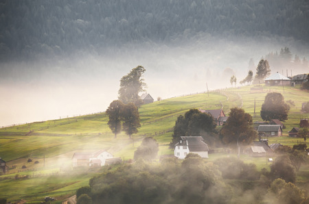 Alpine village in mountains. Smoke, bonfire and haze over the hills in Carpathians.の写真素材