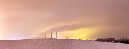 Thermal power plant and cooling towers at night near the cityの写真素材