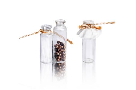 Three small glass vial with brown pills on the white. Vials are tied with twine.の写真素材