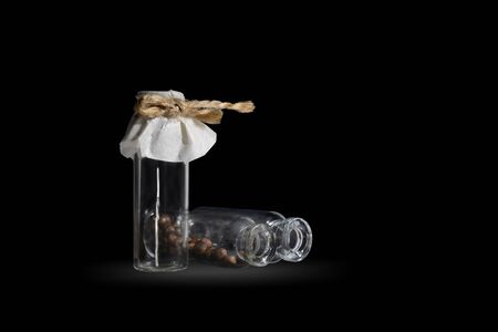 Three small glass vial with brown pills on the black. Vials are tied with twine.の写真素材