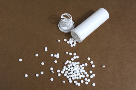 White plastic vials with pills on brown cardboard backgoundの写真素材