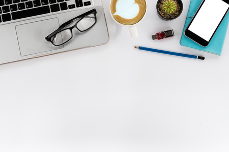 White office desk table with blank screen smartphone, pencil, leather notebook, flatdrive, laptop, glasses and cup of coffee. Top view with copy space.Office desk table concept.の写真素材